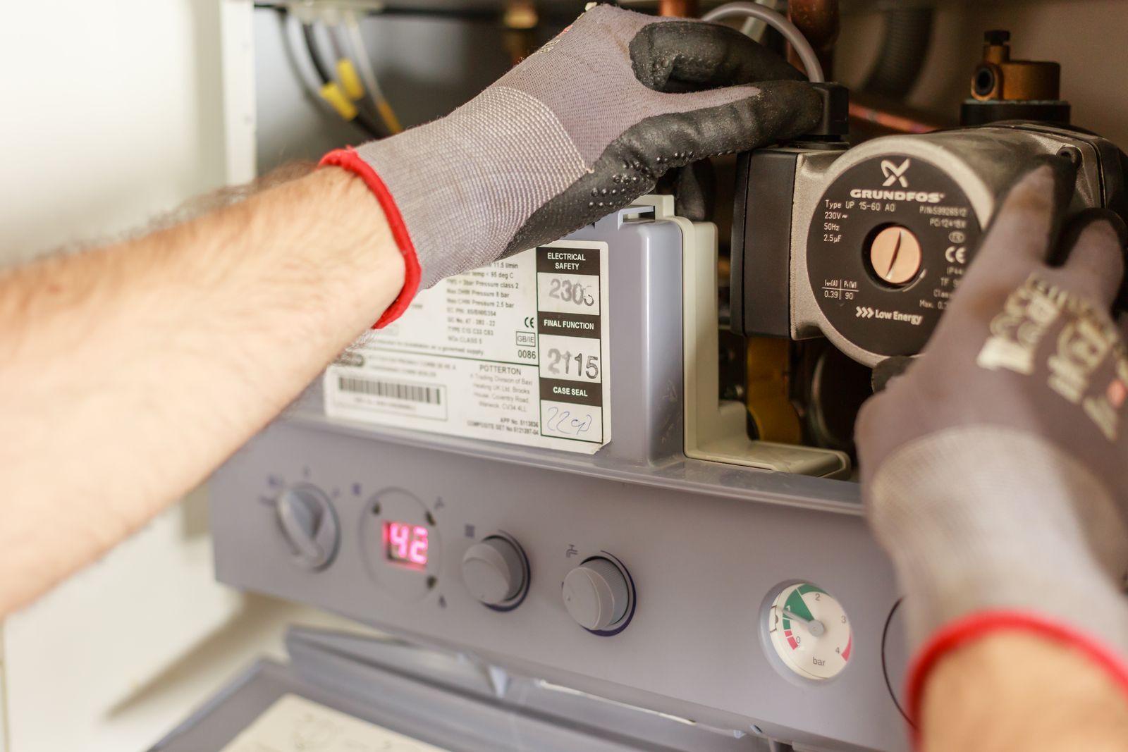Hands installing a boiler pump during a plumbing installation